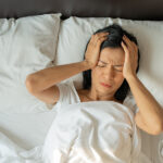 Unhappy exhausted mature woman with closed eyes lying in bed, to
