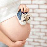 Pregnant woman holding small shoes