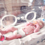 Foto de um bebê deitado na incubadora.